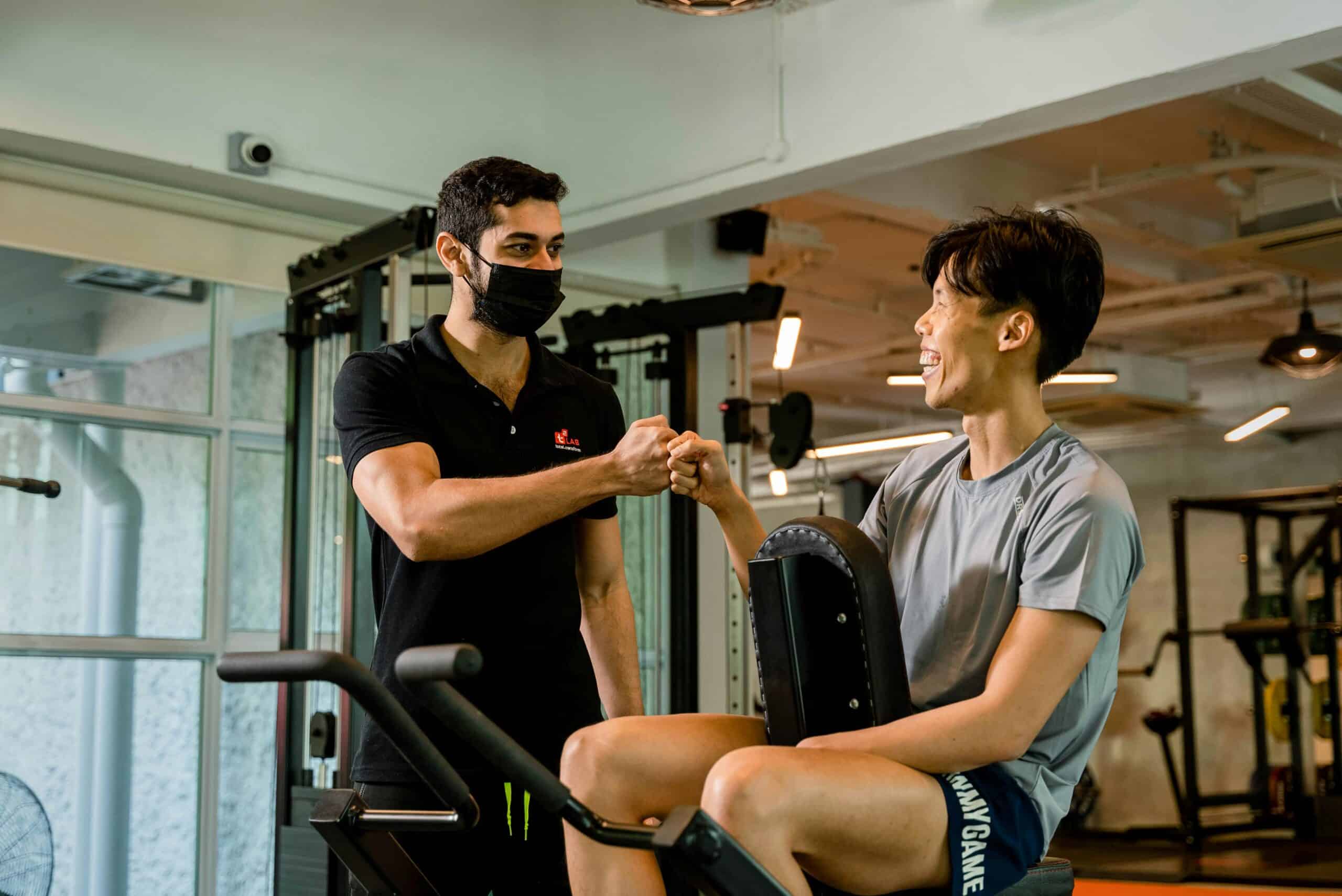 Personal trainer and client fist bumping after a successful coaching session